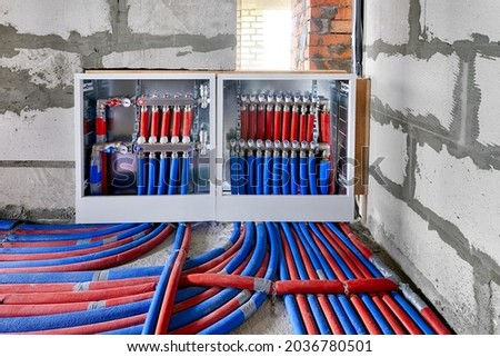 Heating system manifold valves for heat flooring and water supply in a country house. Pipes collector in a building under construction Royalty-Free Stock Photo #2036780501