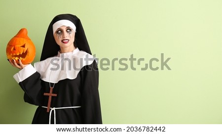 Woman dressed for Halloween as nun with pumpkin on color background Royalty-Free Stock Photo #2036782442