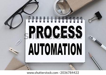 PROCESS AUTOMATION. text on white paper on gray background near magnifier and glasses