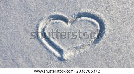 drawing on a snow surface in the shape of a heart in the winter season, a heart symbol drawn on snow