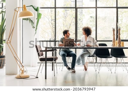 Young multiracial colleagues sharing ideas in bright co working loft office. Huge window. Coworking concept. Business meeting concept. Startup concept. Copy space. Royalty-Free Stock Photo #2036793947