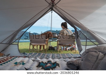 Looking out from the inside of the tent, the golden retriever accompanies the owner Royalty-Free Stock Photo #2036801246