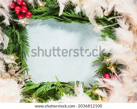Green fir tree branches frame with star shape Christmas lights and red ornament decor, feathers. New year winter background