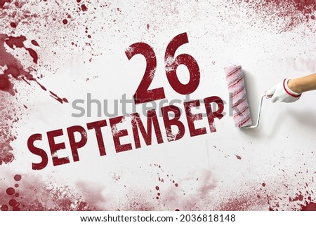 September 26th. Day 26 of month, Calendar date. The hand holds a roller with red paint and writes a calendar date on a white background. Autumn month, day of the year concept