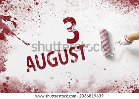 August 3rd. Day 3 of month, Calendar date. The hand holds a roller with red paint and writes a calendar date on a white background. Summer month, day of the year concept