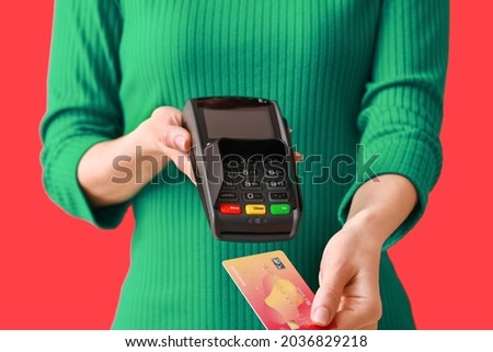 Young woman with payment terminal and credit card on color background, closeup