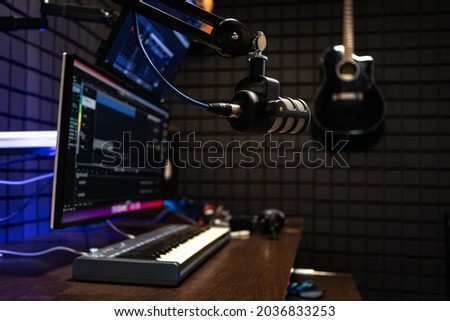 Modern music recording studio equipment. Computer screen showing user interface of digital audio workstation software with track song on a sound acoustical foam background in recording studio