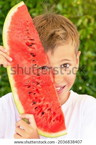 Happy child (boy) with red juicy watermelon. Caucasian kid smiling 
and having fun. Concept of healthy food, happy childhood, summer vacation. Nature green background. 