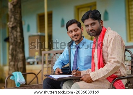 young india bank officer completing paper work with farmer at his home.