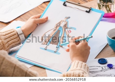 Female fashion designer working with sketches in studio, closeup Royalty-Free Stock Photo #2036852918