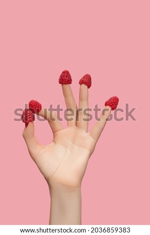 Female hand five fingers with sweet raspberries hats on nails showing ok sign isolated on pink background. Female hand show OK gesture.