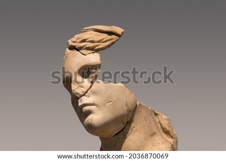 closeup portrait of antique damaged stone bust statue depicting a woman head with large pieces missing from the face area and large cracks in the marble Royalty-Free Stock Photo #2036870069
