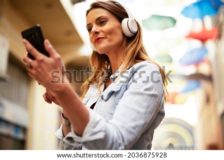 Young smiling woman with headphones outdoors. Beautiful woman listening the music