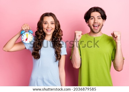 Photo of young happy couple hold hand clock alarm winner celebrate good mood isolated on pastel pink color background