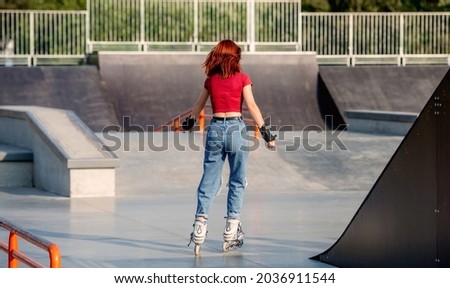 Pretty girl on roller skates practicing riding at park ramp. Female teenager rollerblading at summer outdoors portrait from back