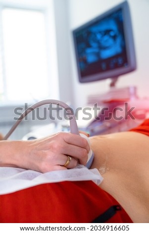 Pregnant woman getting ultrasound from doctor. Ultrasound equipment in clinic. Selective focus on belly