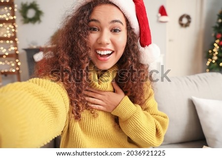 Young African-American woman in Santa hat greeting her family on videocall due to coronavirus epidemic