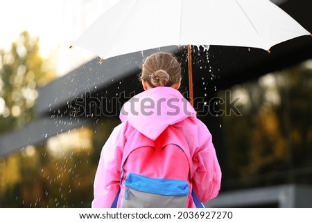 Beautiful young woman with umbrella wearing raincoat outdoors