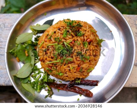 Stock photo of delicious popular South Indian rice dish puliyogare, its also called pulihora or puliyodarai garnished with dry chilli fresh coriander and curry leaves. one dish meal.