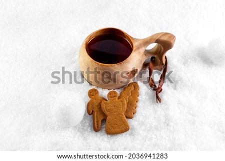 Kuksa with tea and gingerbread cookies in the snow. Finnish traditional wooden cup. Photo
