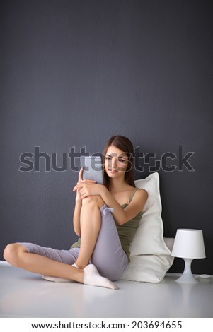 Pretty brunette woman sitting on the floor with a pillow and plane table