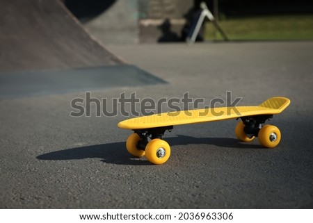 Modern yellow skateboard on asphalt road outdoors
