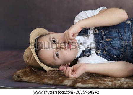 a boy with a painted mustache lies on the floor posing for a camera