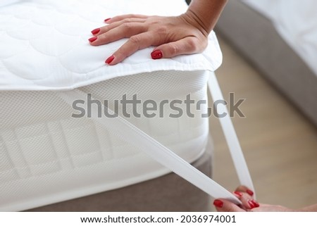 Woman puts blanket or mattress topper on bed closeup Royalty-Free Stock Photo #2036974001