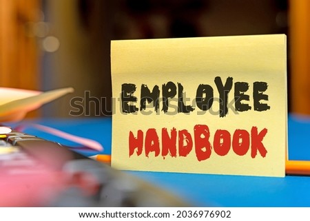 Text caption presenting Employee Handbook. Business idea states the rules and regulations and policies of a company Multiple Assorted Collection Office Stationery Photo Placed Over Table