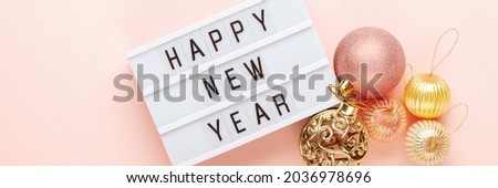Christmas balls and lightbox with the text "Happy New Year" on a pink background. Flat lay. Banner