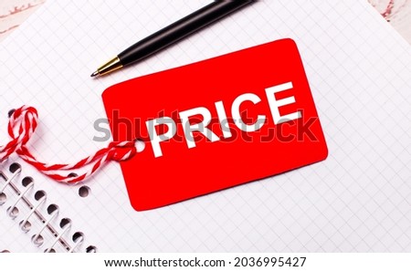 On a white notebook there is a black pen and a red price tag on a string with the text PRICE.