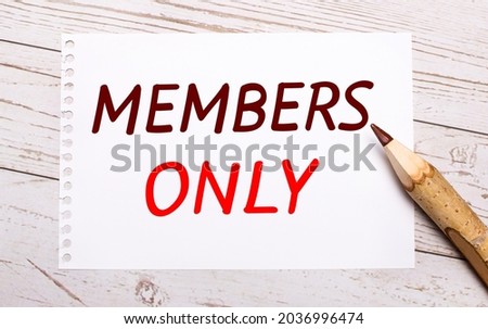 On a light wooden background, a colored pencil and a white sheet of paper with the text MEMBERS ONLY