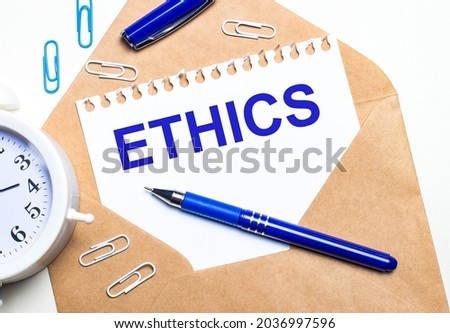 On a light background, a craft envelope, an alarm clock, paper clips, a blue pen and a sheet of paper with the text ETHICS.