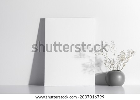 White canvas mockup with shadow and vase with gypsophila on white table