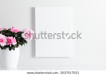 White canvas mockup and vase with pink flowers on white table