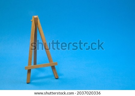 Small empty easel on bright blue background, close up with copy space