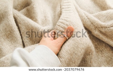 Hand touching knitted wool cloth or warm fluffy sweater. Handcraft knitting woolen fabric surface.  Royalty-Free Stock Photo #2037079676