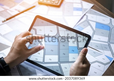 a man searching building plot on a cadastral plan to choose and buy a building plot for house construction on a digital tablet Royalty-Free Stock Photo #2037089369