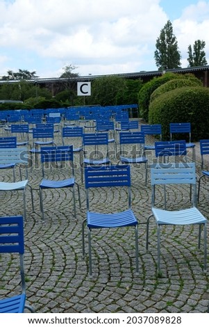 on the paving stones are many blue chairs empty