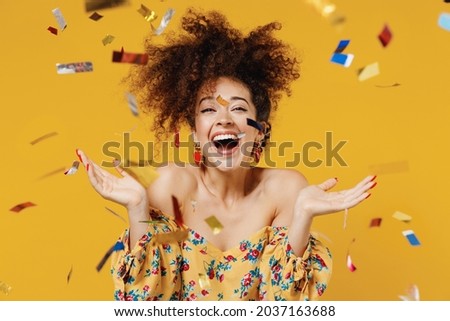 Young happy satisfied excited fun surprised amazed woman 20s with culry hair in casual clothes tossing throwing confetti isolated on plain yellow background studio portrait. People lifestyle concept Royalty-Free Stock Photo #2037163688