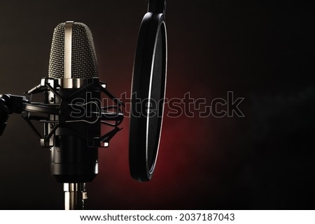 Professional studio microphone on a black-red background. Recording in a sound recording studio. Vocals, conversational genre, television, radio broadcasting. Advertising. Minimalism.