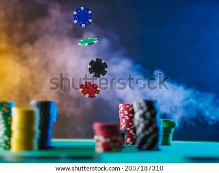 Casino. There are stacks of multi-colored chips on the table. Some of the chips are in a state of levitation. In the background, colorful smoke. Gambling, poker, gambling business, casino.