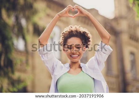 Photo of cheerful happy positive nice afro american woman make heart shape outside campus outdoors