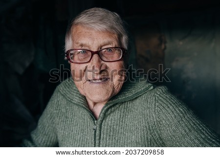 The portrait of an old woman with glasses and a sweater