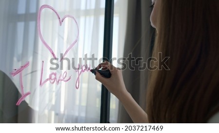 Romantic woman drawing heart on glass