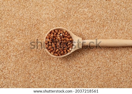 Organic buckwheat in wooden spoon on background of Buckwheat Flour (ground grits) or flake.