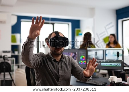 Video editor experiencing virtual reality headset, gesturing, editing film montage using post production software working in creative company office. Videographer using VR headset in multimedia agency