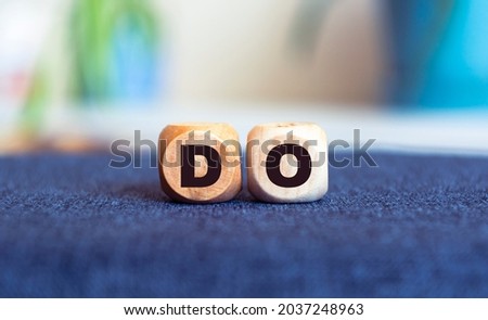 Word do. Top view of wooden blocks with letters on blur background.