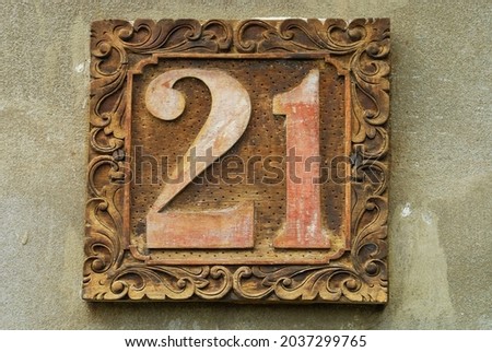 An aged wooden address sign with "twenty-one" written on it