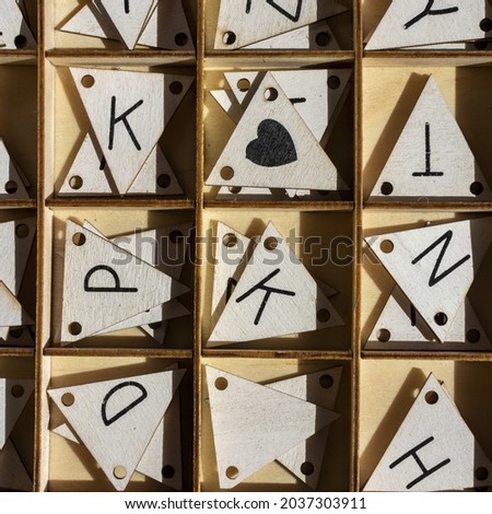 A top view of a wooden box with triangle-shaped wooden letters inside